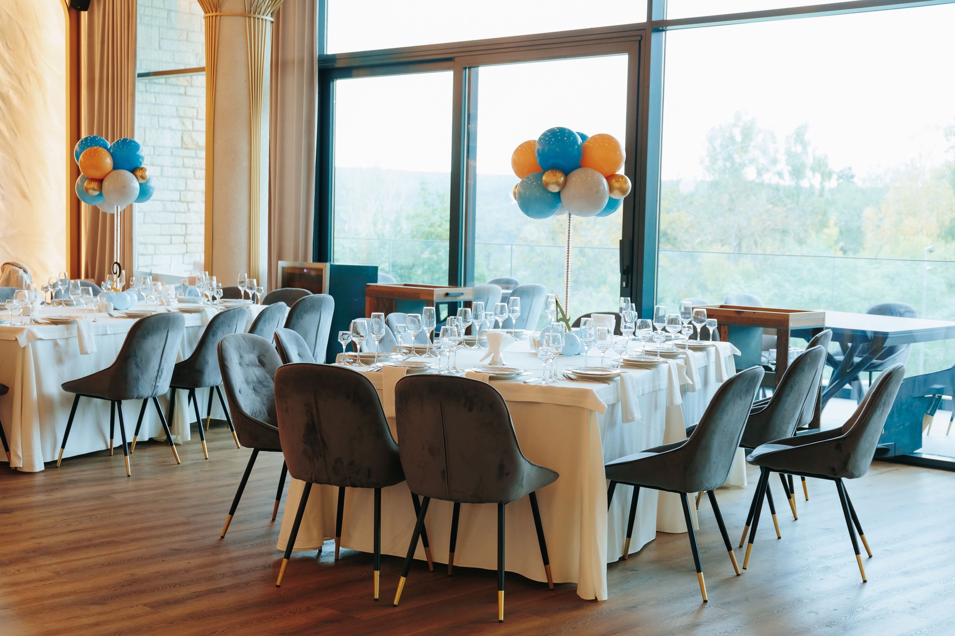Elegant banquet venue with balloon centerpiece and scenic window views.